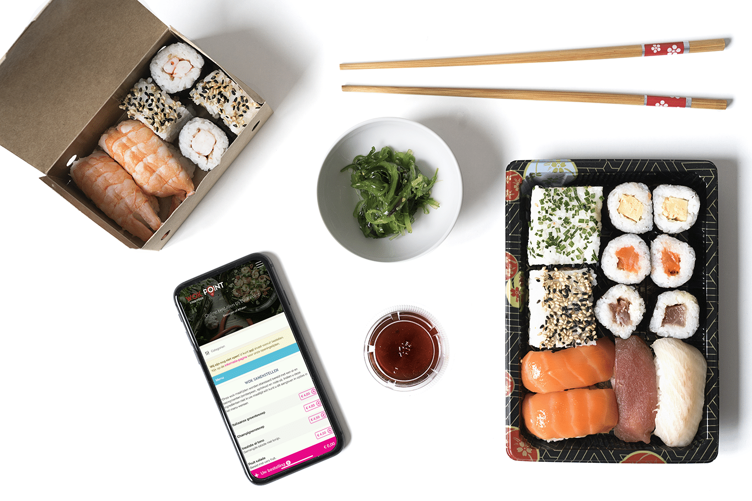 Bovenaanzicht van sushi met bijgerechten, smartphone en eetstokjes.
